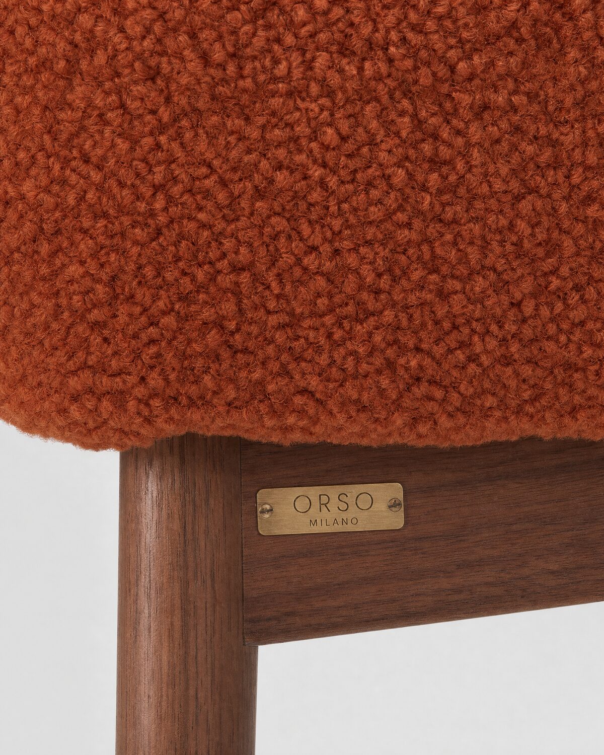 Lounge armchair in rust bouclé and walnut, close-up