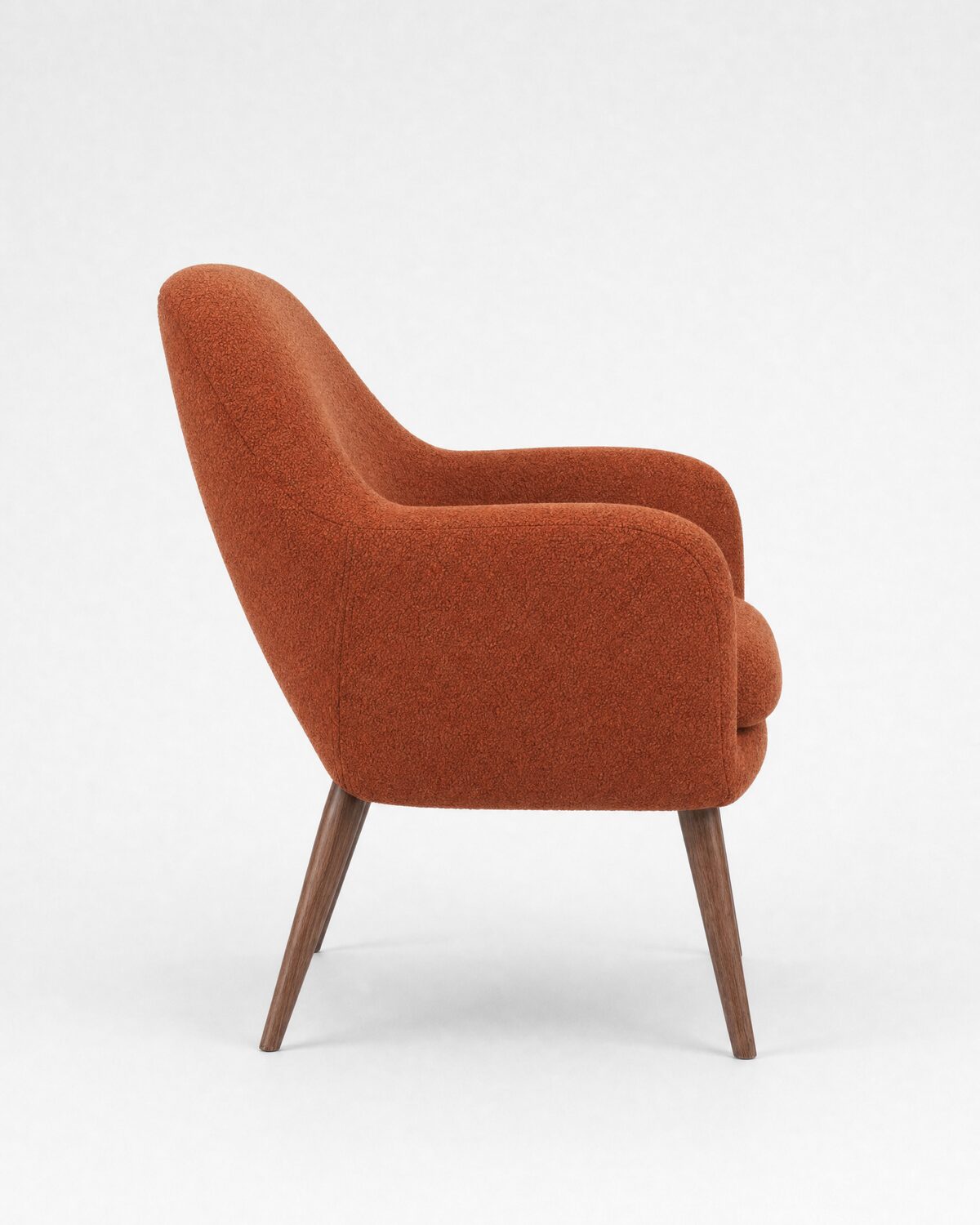 Lounge armchair in rust bouclé and walnut, side view